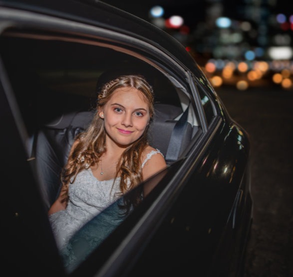 Quinceañera llegando a su fiesta en auto durante la noche, retrato íntimo capturado por Caro Roig Fotografía en Montevideo