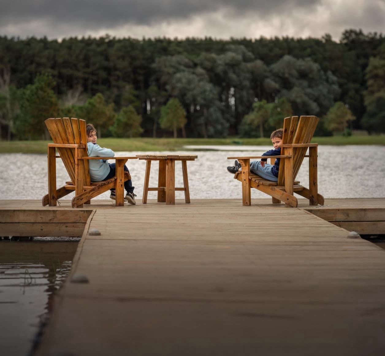 foto de exteriores en la que se ve a dos ninos en una silla viendo un lago