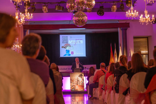 Conferencia en auditorio por el Día Internacional de la Mujer, con público y expositor en escenario – fotografía de eventos por Caro Roig.