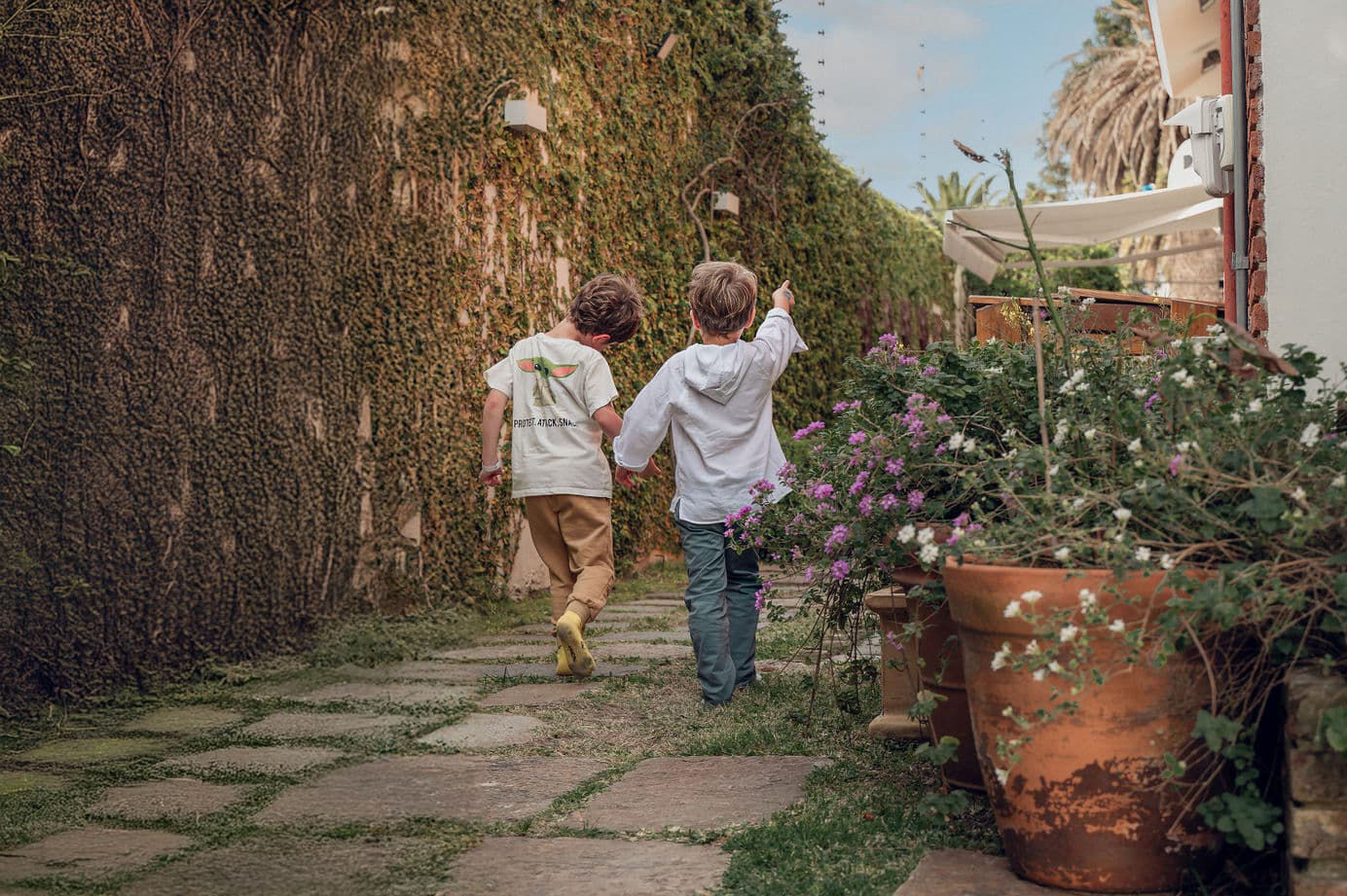 Dos niños caminando tomados de la mano durante un cumpleaños infantil en Carrasco, Montevideo, captados en un momento espontáneo.