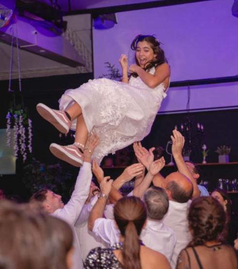 Chica levantada en el aire en un momento espontáneo y alegre durante fiesta de 15 años en Uruguay, fotografía emocional de Caro Roig